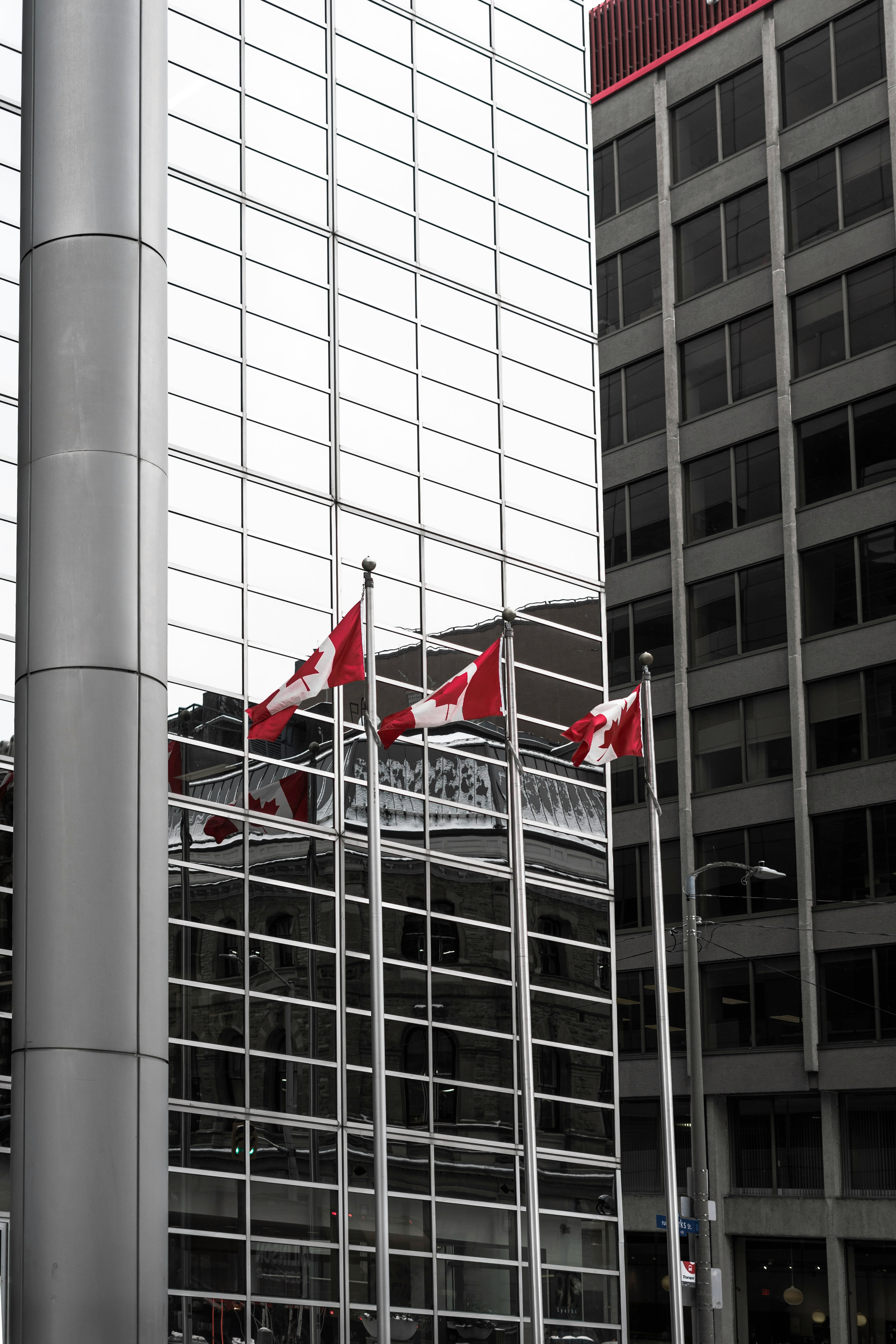 the canadian flag is flying in front of a glass building
